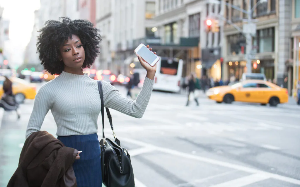 Woman with mobile device waiting for rideshare car service