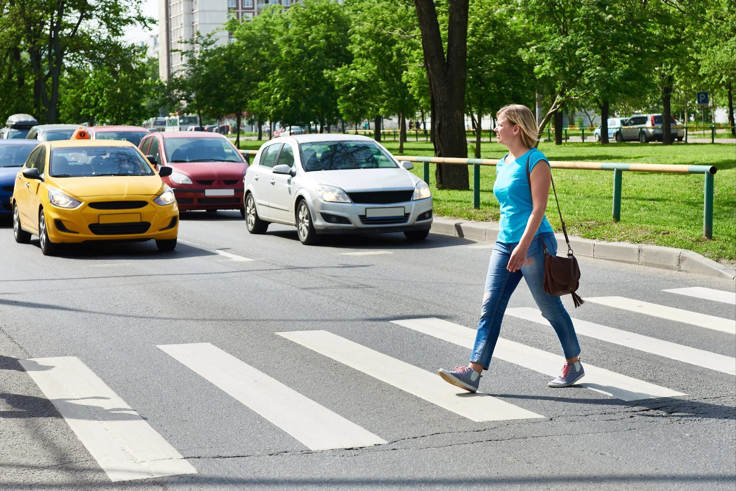 Woman walking across a crosswalk with vehicles approaching in adjacent lanes