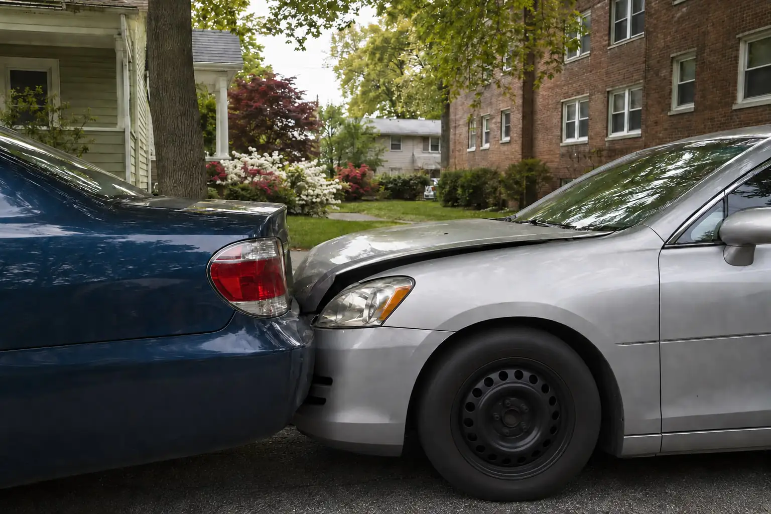 Two sedans after a rear-end collision beside low-rise homes, illustrating a Spring Valley NY car accident.