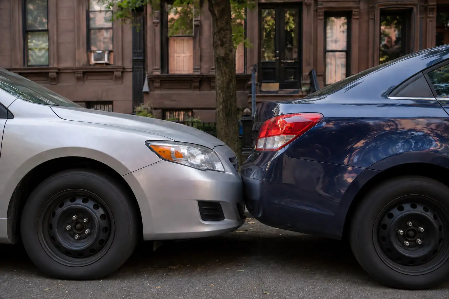 Two sedans after a rear-end collision beside brownstone homes, illustrating a Bedford-Stuyvesant NY car accident.
