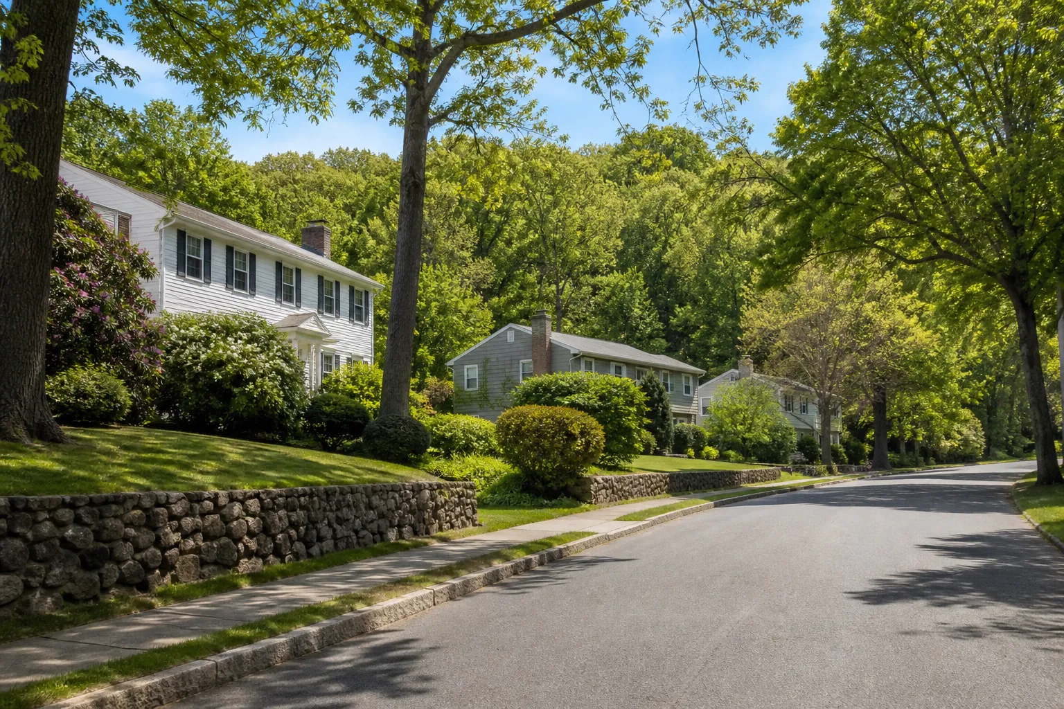 Clarkstown NY leafy suburban street with mature trees, stone walls, and low-rise homes