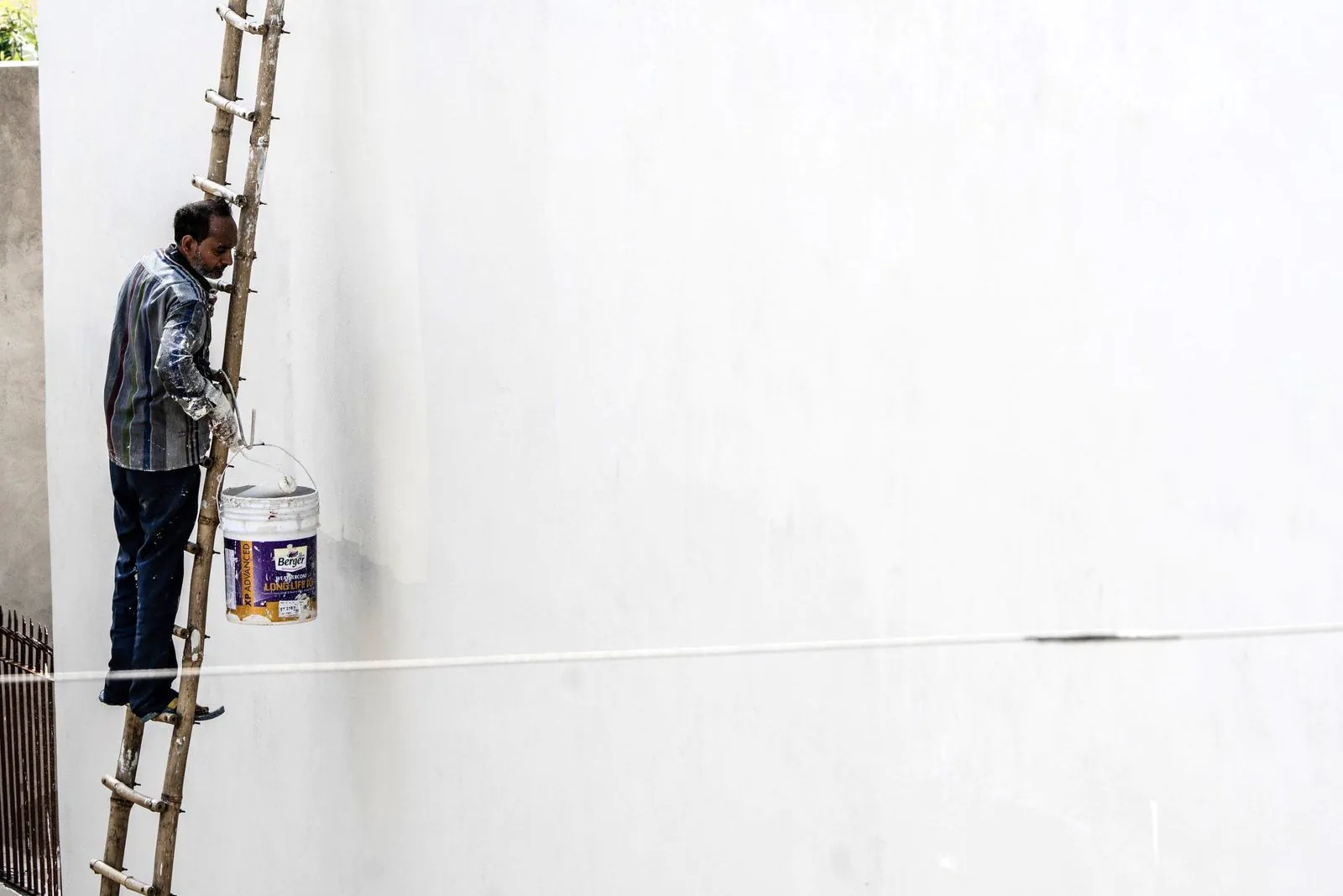 Worker standing on a ladder holding a paint bucket