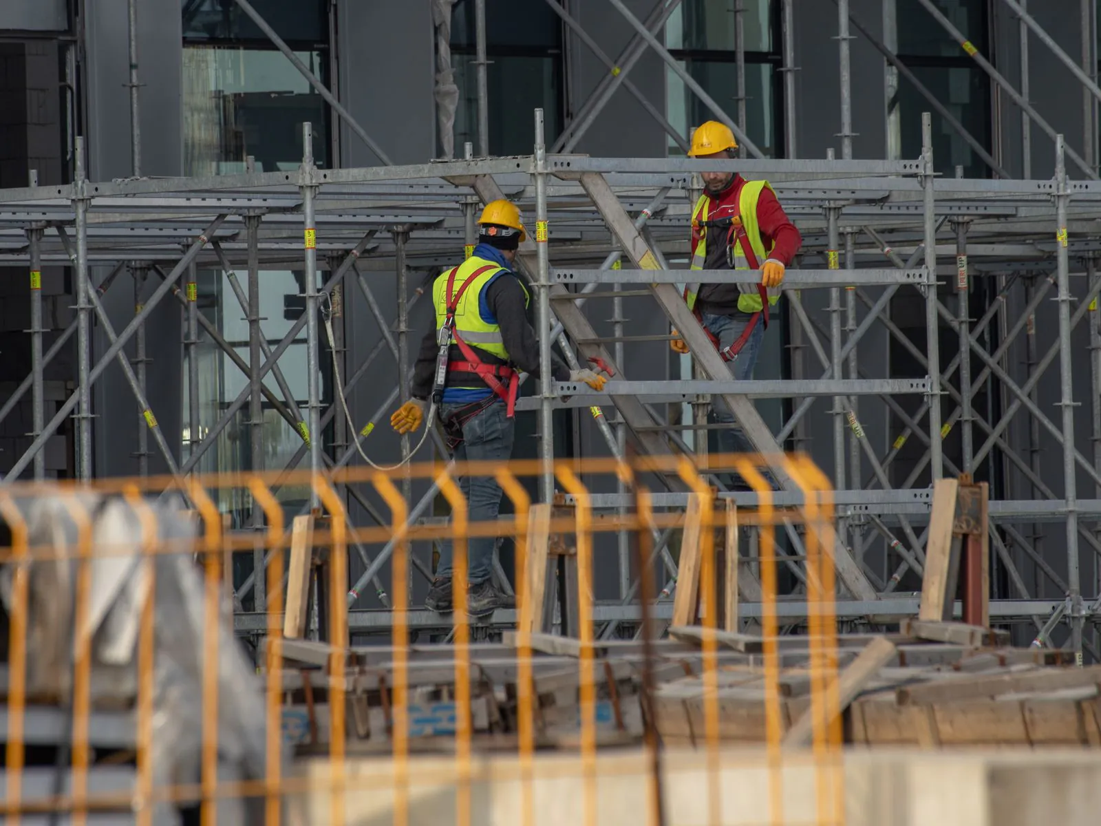 Workers wearing harnesses on a scaffold at a city construction site