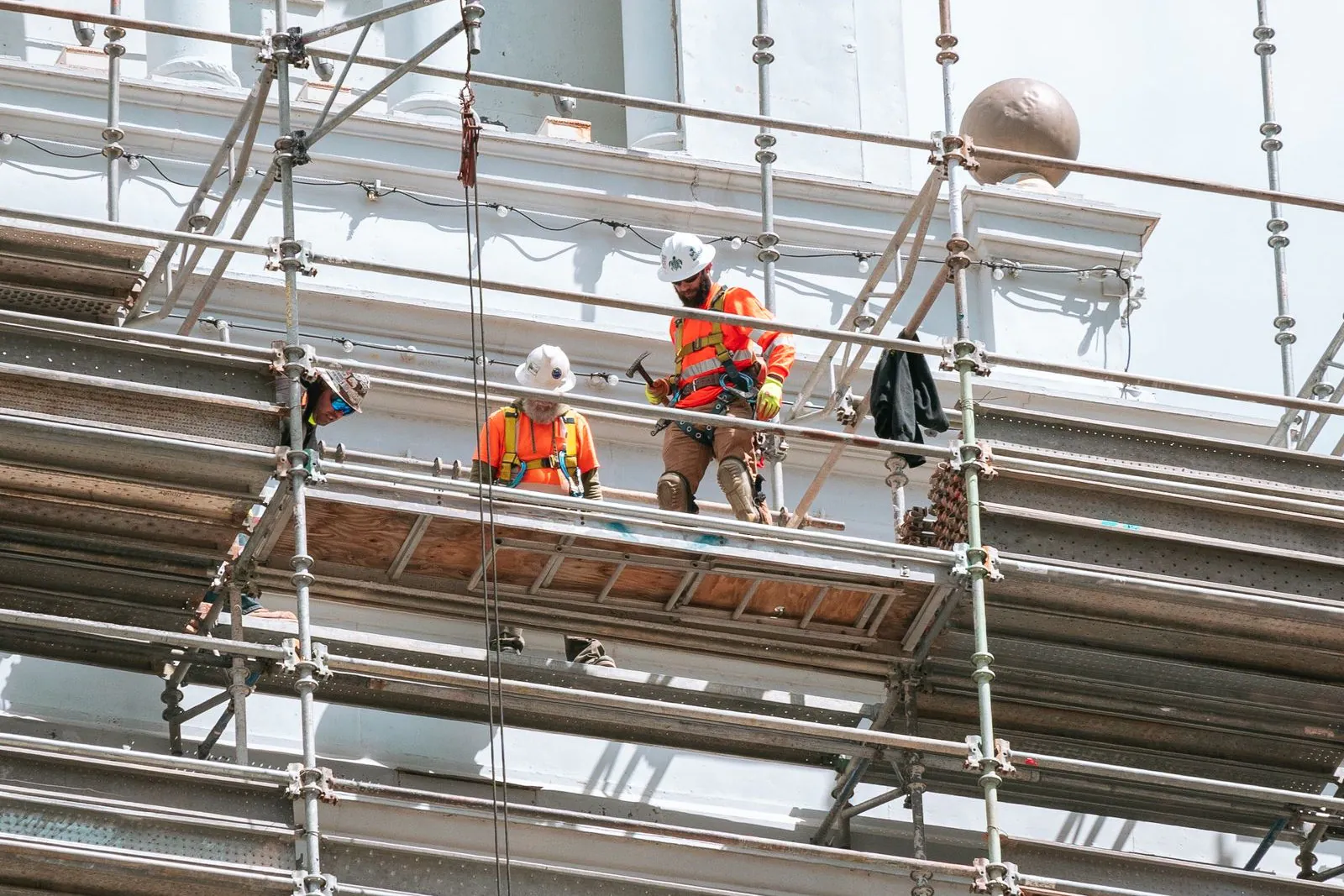 Two construction workers in hard hats standing on scaffolding at a building site